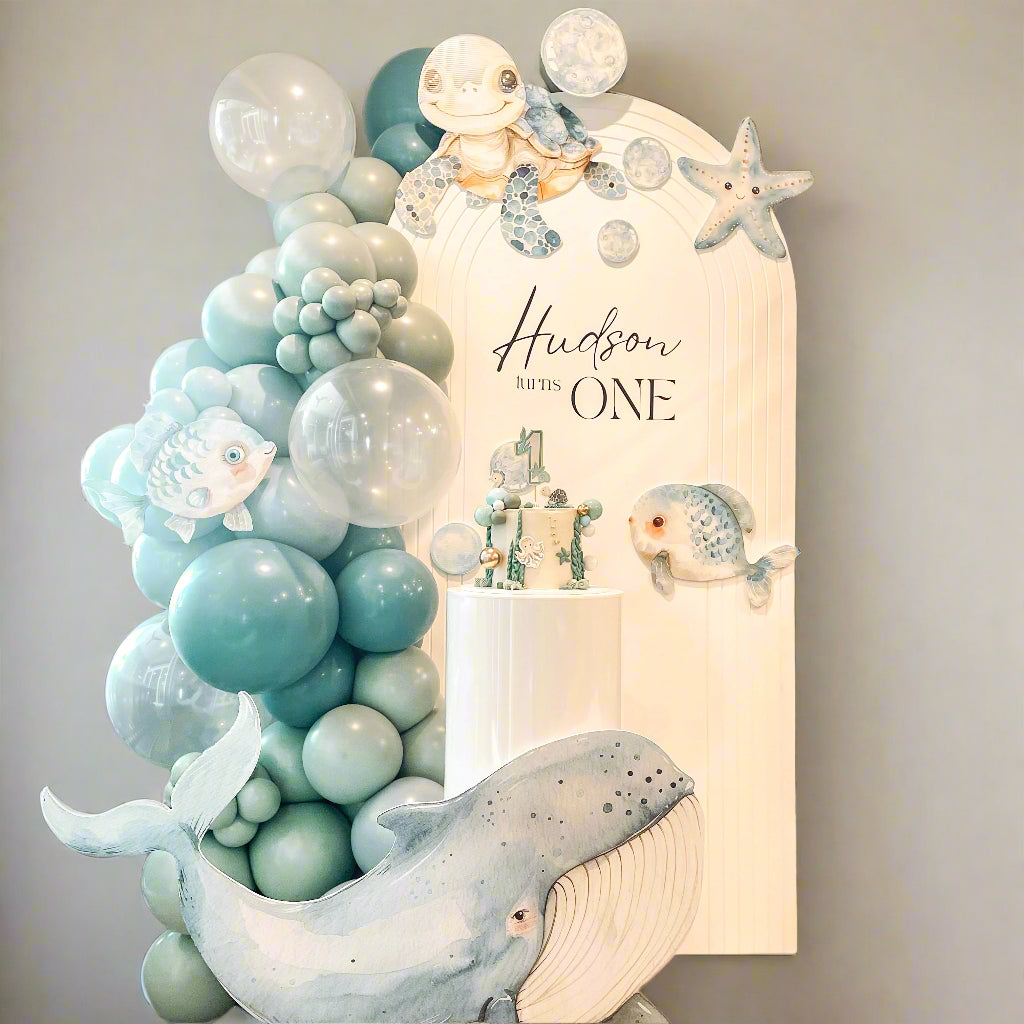 Decorative setup with balloons, a whale, and a 'Hudson is ONE' sign in a room.