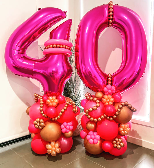 Two pink foil balloons designed to form the number '40' with additional decorative elements.